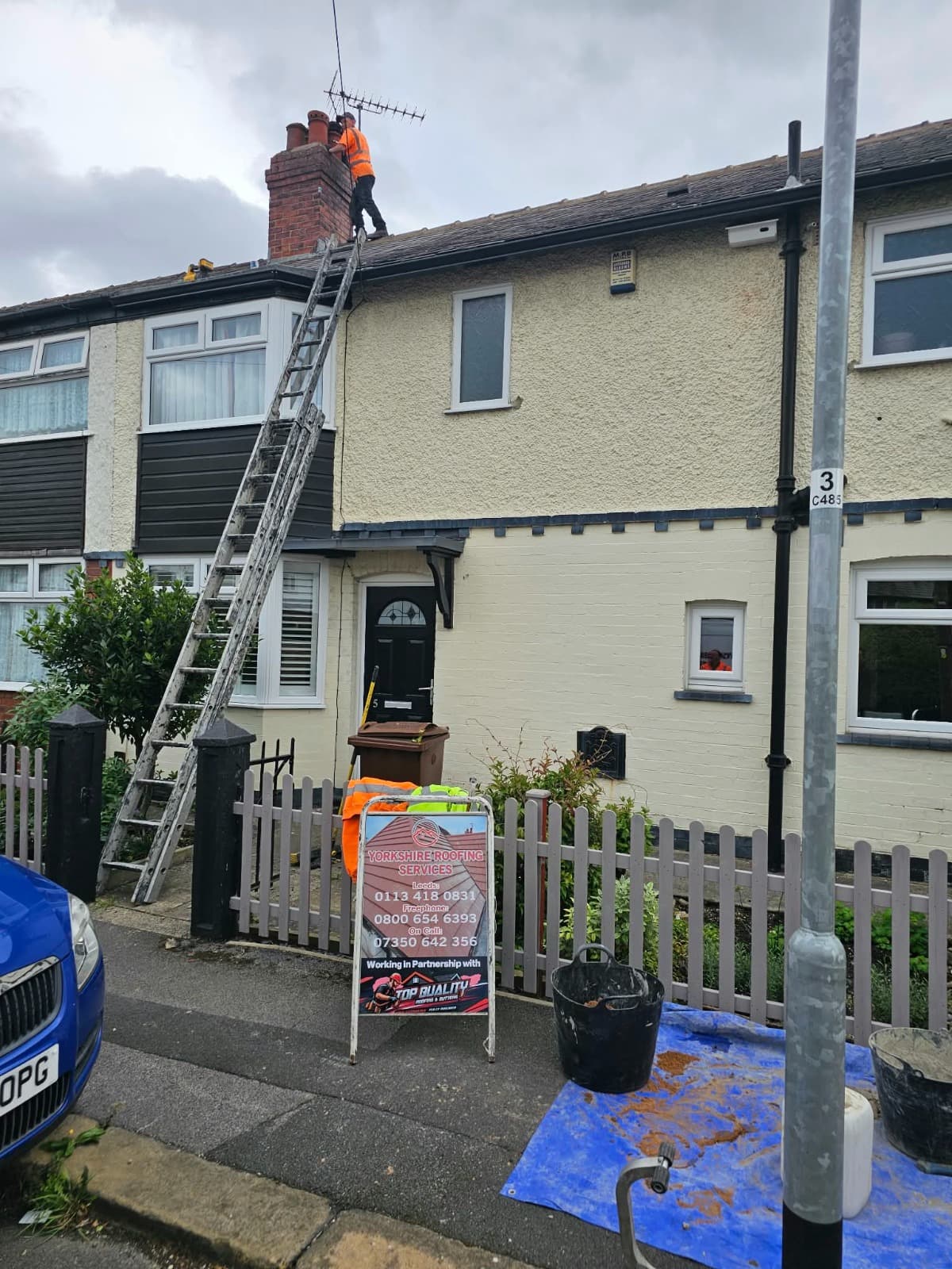 Roofer accessing a chimney and roofline by ladder for an inspection